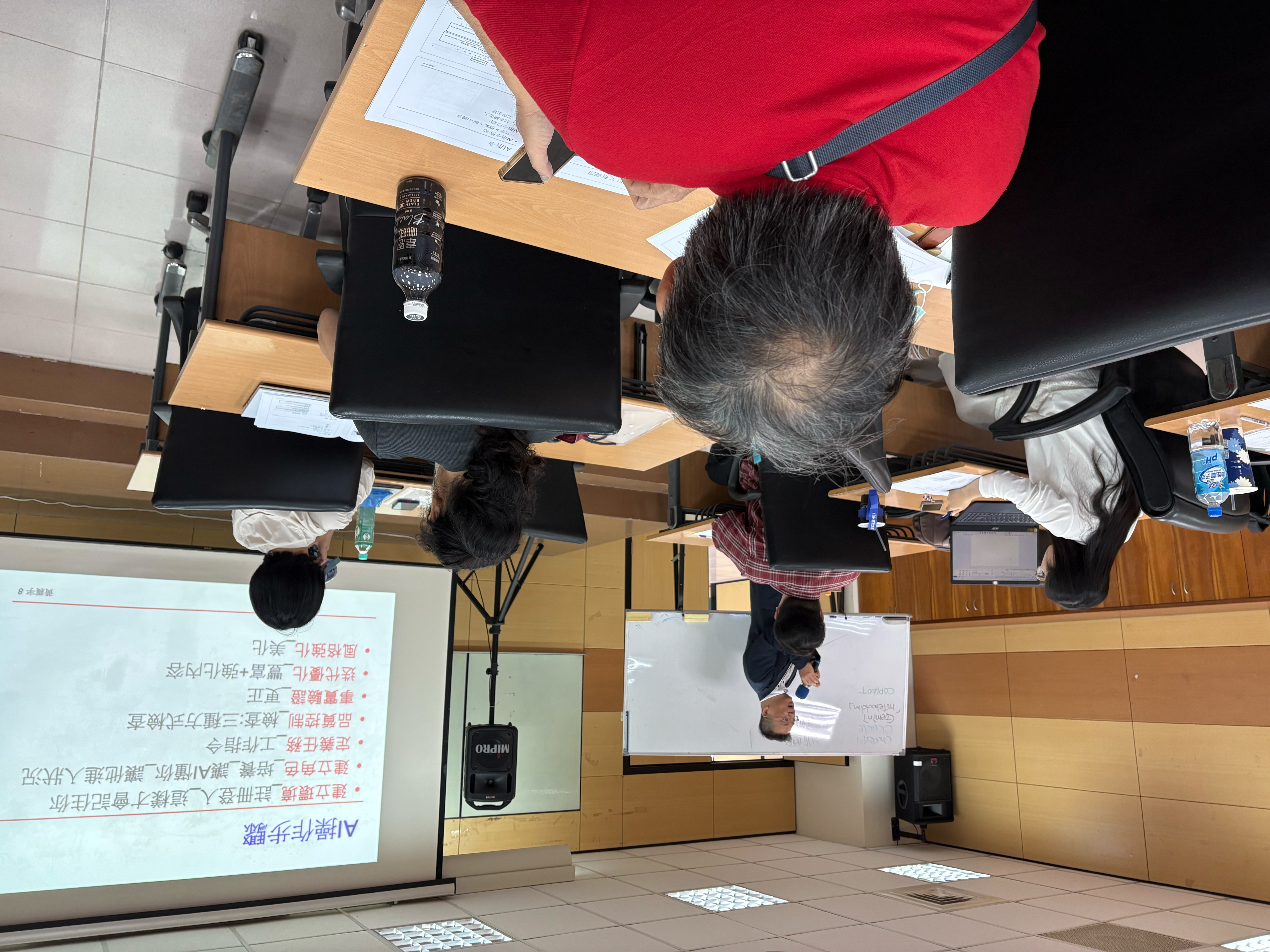 黃震宇老師在新營民治中心講解AI操作步驟，投影簡報展示資料培養與內容品質檢查